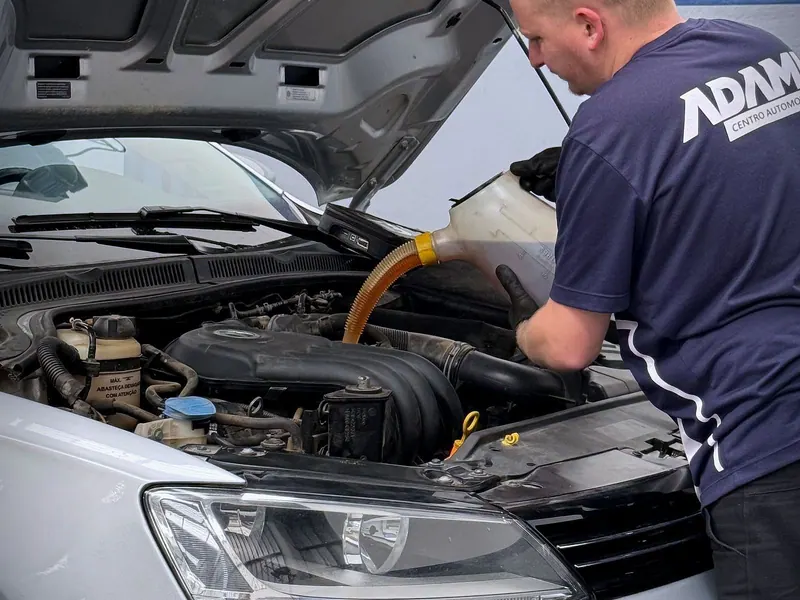 Mecânico do Adami colocando óleo no motor de um carro